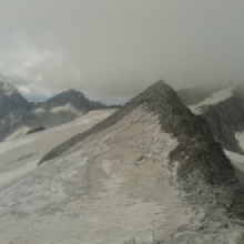 A destra, coperta dalle nuvole, la cima del Monte Magro. Il sentiero passa sul ghiacciao a sinistra del primo cucuzzolo in foto.